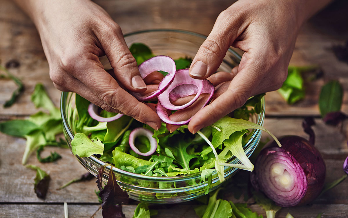 Vegan Blog Digestive Health Mâini care taie ceapă roșie peste o salată