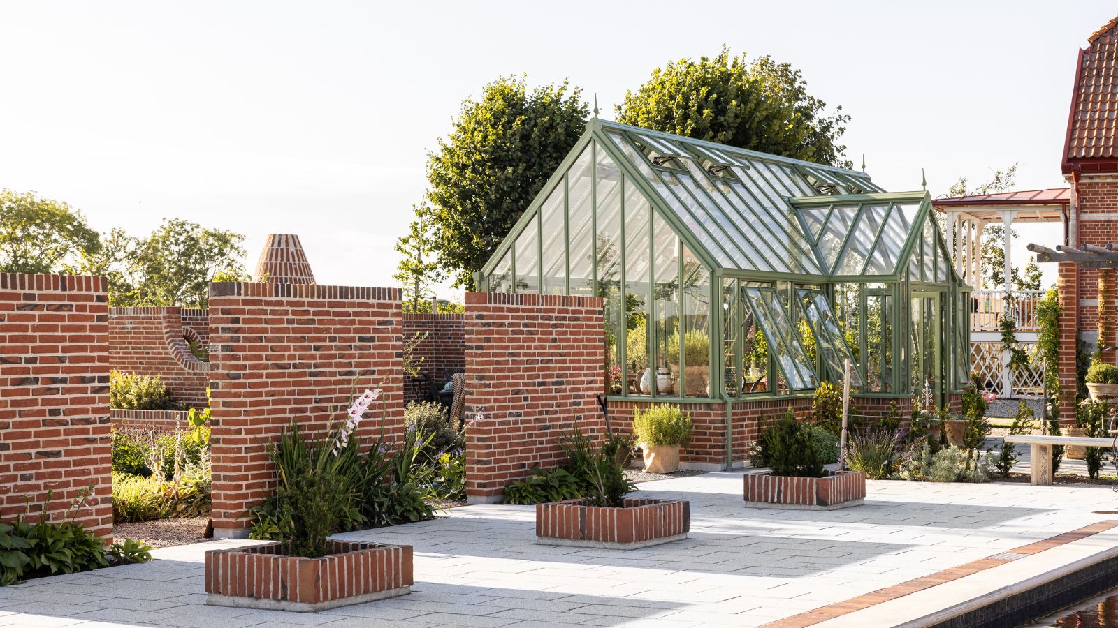 Glass gardens bespoke 8 Oranjerie cu ramă verde pe terasă, între ziduri de cărămidă și jardiniere