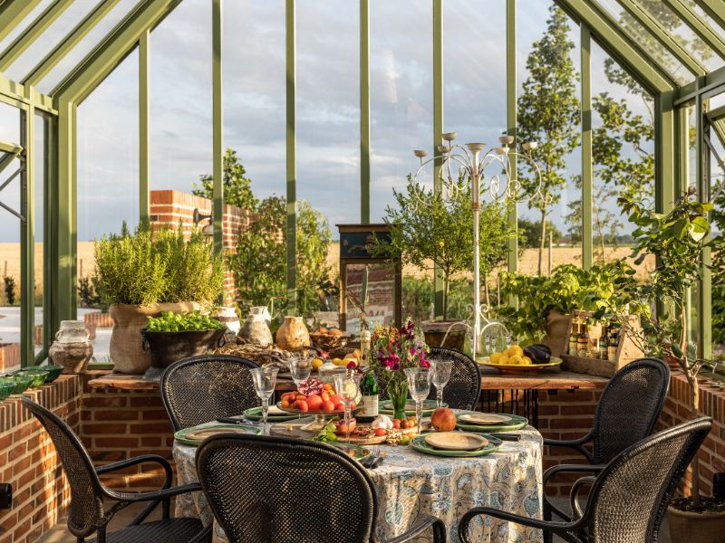 Interiorul oranjeriei Grandiflora, cu masă pusă și zid de cărămidă