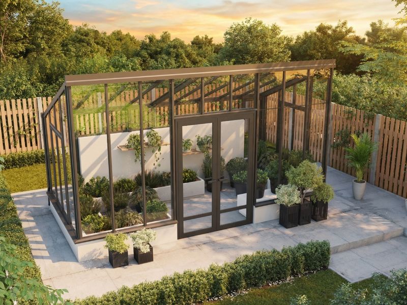 Oranjerie minimalistă Sanctuary Mini la apus, cu uși duble și jardiniere pe terasa pavată