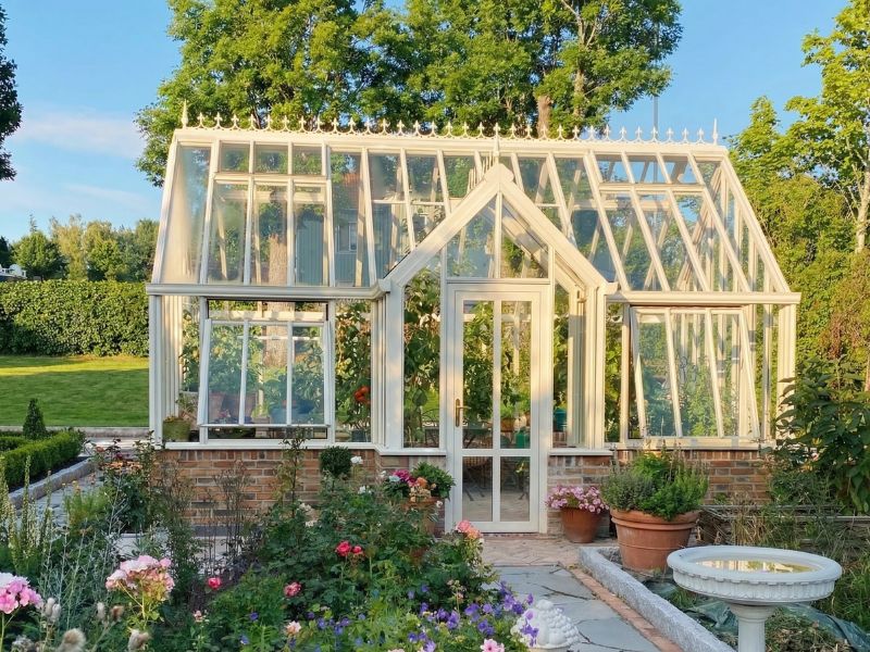 Oranjerie Floribunda cu verandă frontală, văzută peste un strat de flori